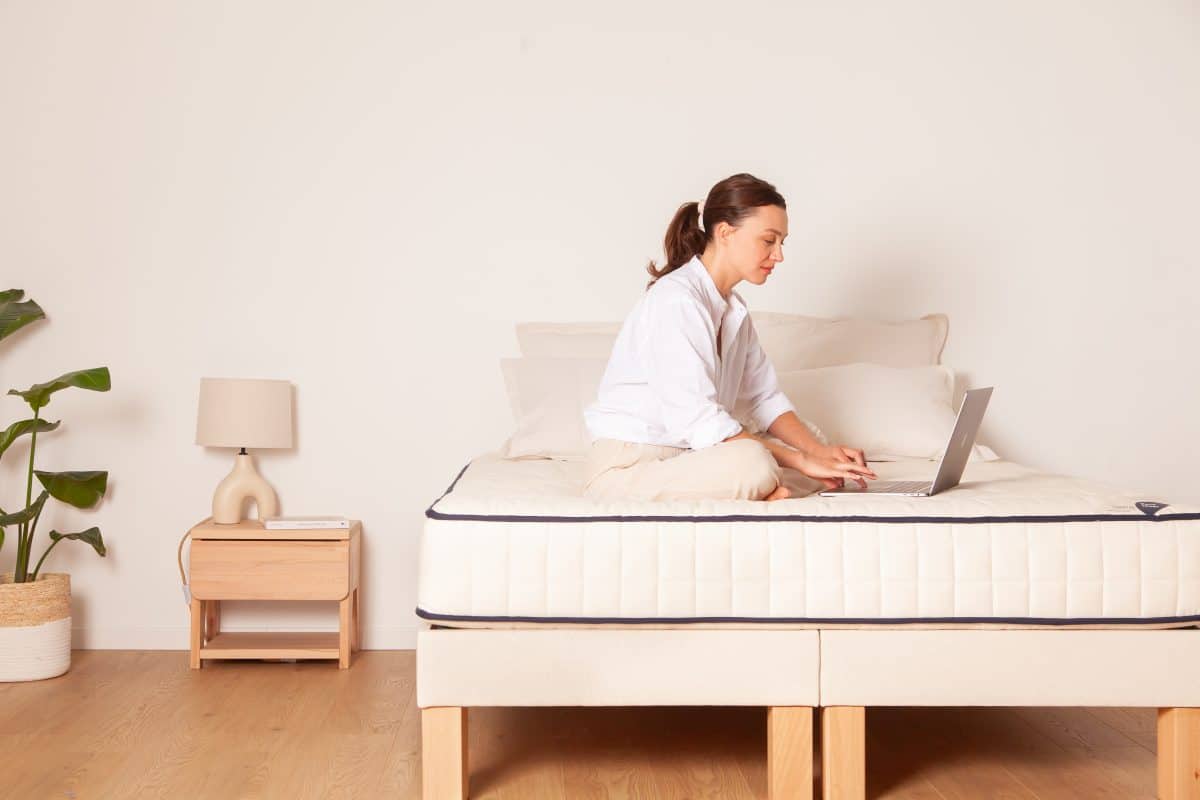 une femme travaillant sur son PC depuis son matelas